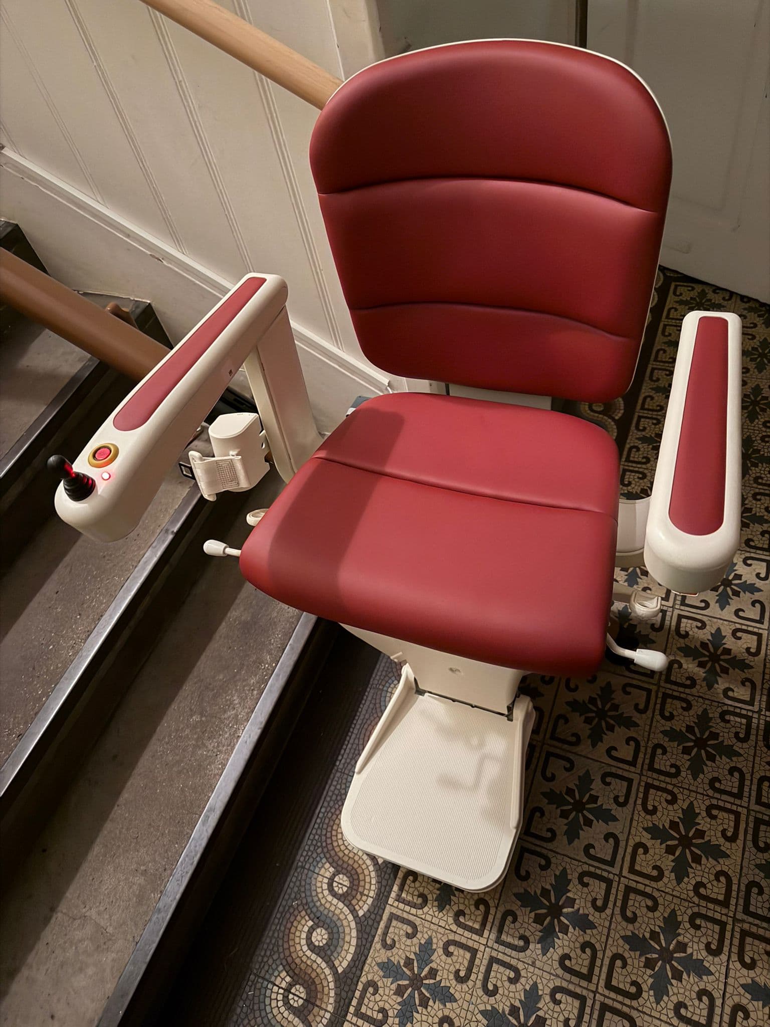 Roter Sitz-Treppenlift auf historischem Mosaikfliesenboden im Altbau