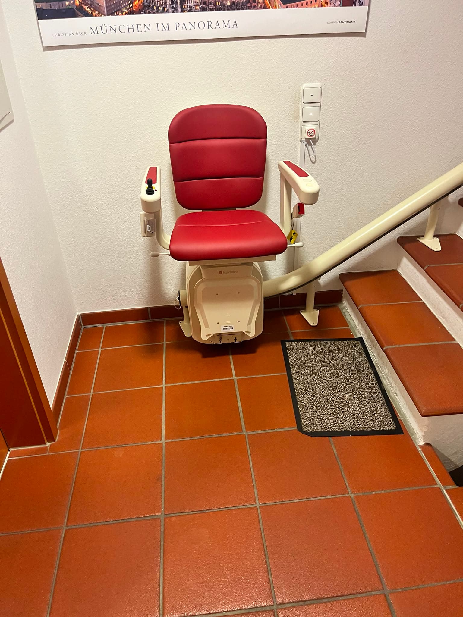 Roter Sitz-Treppenlift im Hausflur mit Terrakotta-Fliesen
