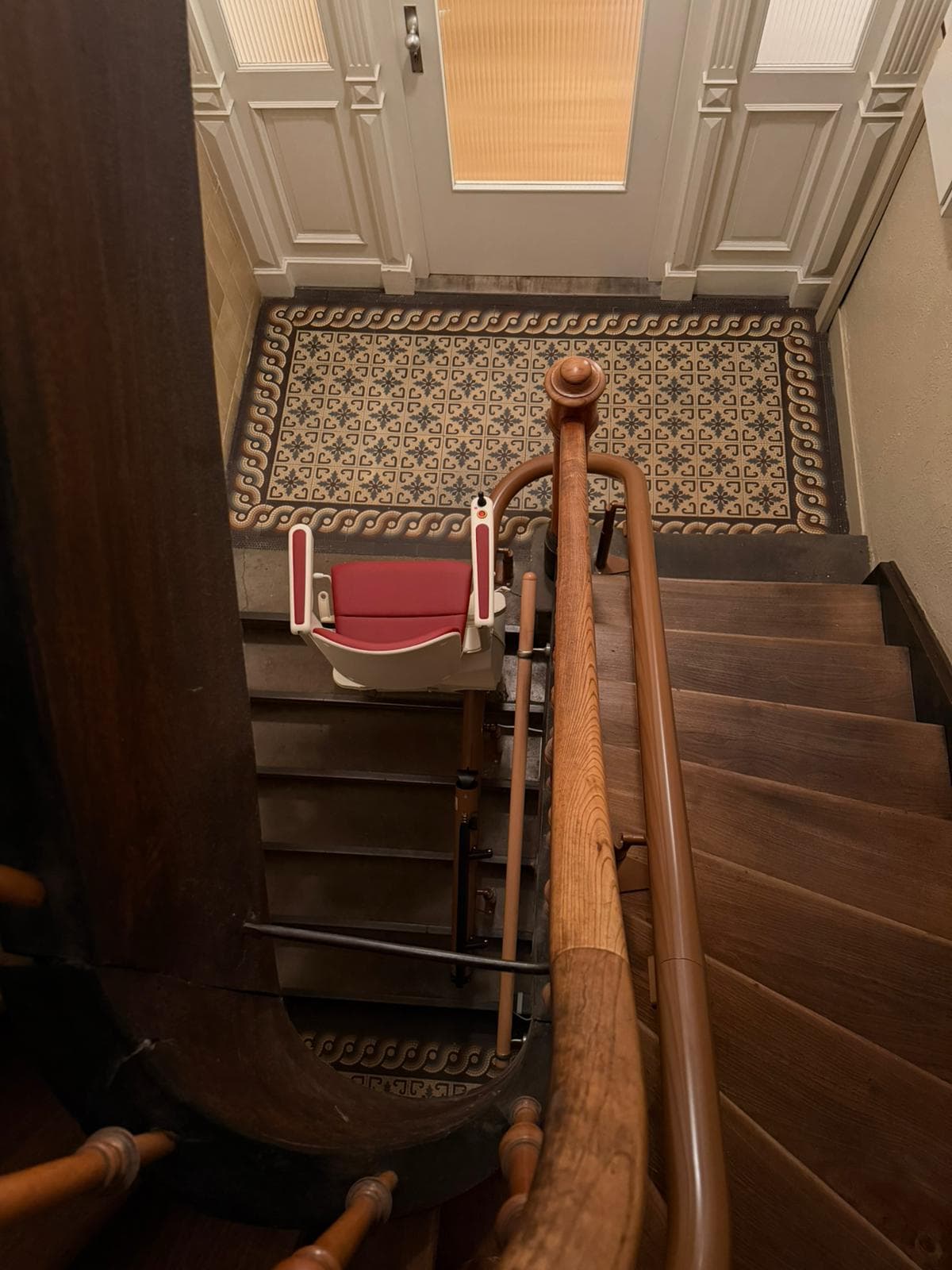 Sitz-Treppenlift auf einer gewendelten Altbautreppe mit Ornamentfliesen