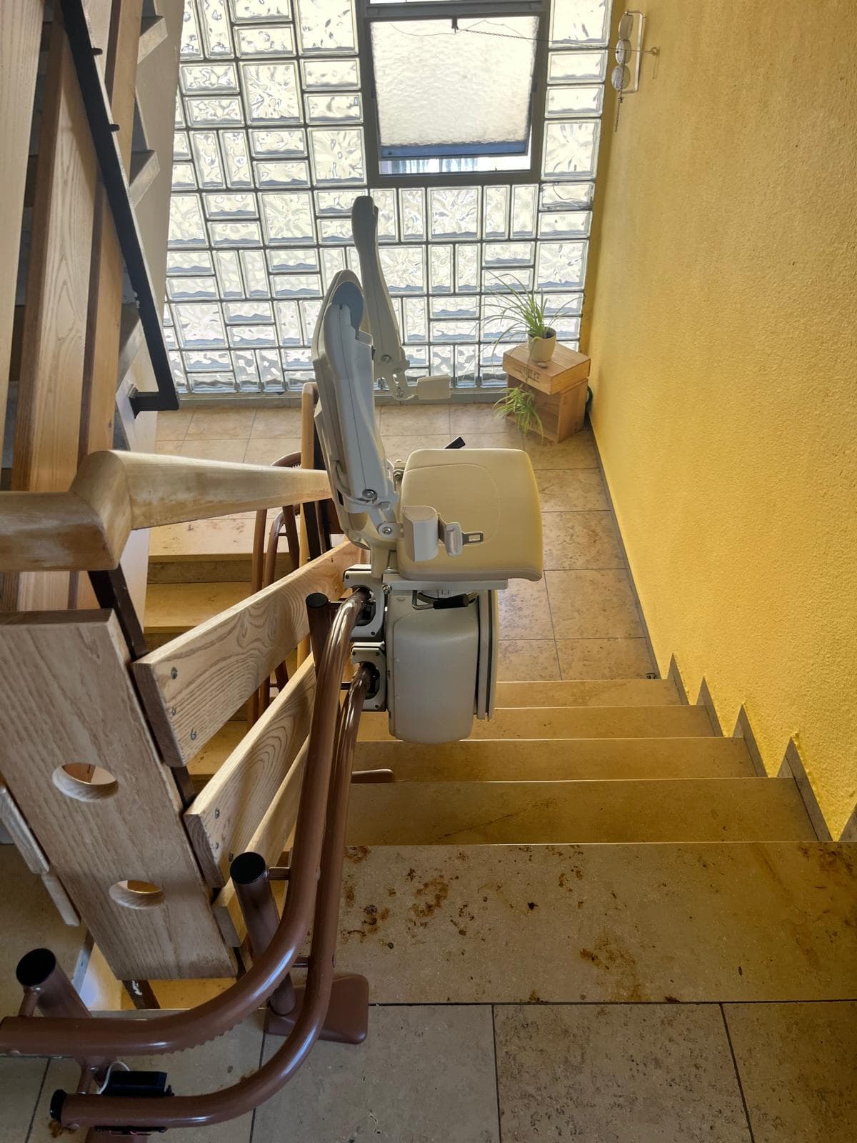Kurven-Sitzlift an einer Innentreppe mit Glasbaustein-Fenster